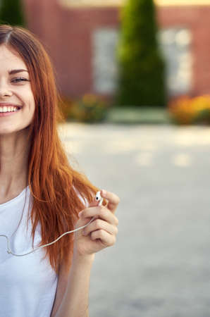 woman in white t-shirt with headphones walking down the street