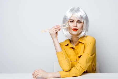 pretty woman in white wig eating sushi rolls restaurantの写真素材