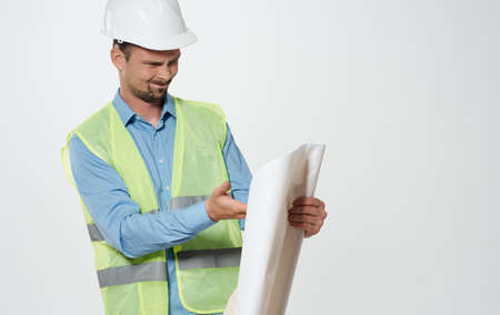 A male civil engineer with a roll of paper in his hands and a white hard hat on his head