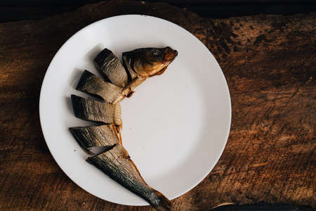 sliced dried fish on a white plate on a wooden tableの写真素材