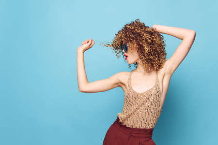 Sexy model Curly hair dark glasses attractive look blue background sequin shirtの写真素材