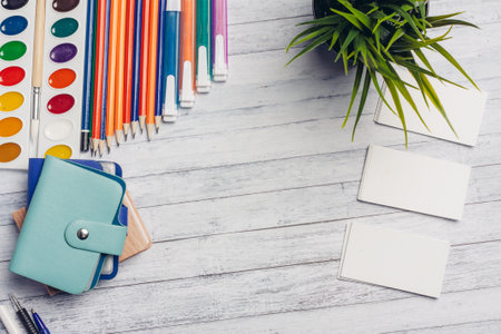 flower in a pot and white business cards on a wooden table office markers pencils paintの写真素材