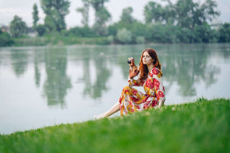 woman in a dress with a camera in nature taking pictures hobbyの写真素材