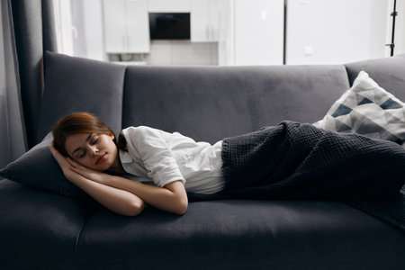 woman with closed eyes resting lying on sofa cropped view close-upの写真素材