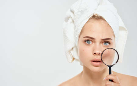 model woman with magnifying glass on light background and towel on head