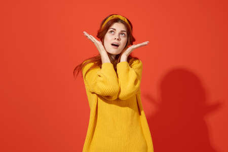 cute red-haired woman in yellow sweater glamor red backgroundの写真素材