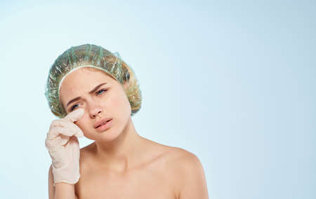 Woman in medical gloves and a transparent cap on a blue background Copy Space cropped viewの写真素材