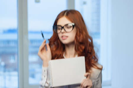 woman in white shirt with notebook in hands of officeの写真素材