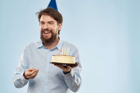 cake in a plate and birthday man with a cap on his head blue backgroun