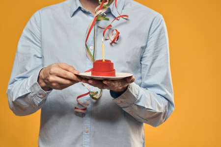A man holding a cake in a plate and a candle from above isolated backgroundの写真素材