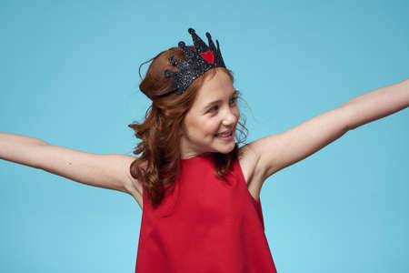 Girl with curly hair with a crown on her head red dress lifestyle blue backgroundの写真素材
