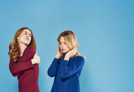 two women in dress conflicts quarrel emotions blue backgroundの写真素材
