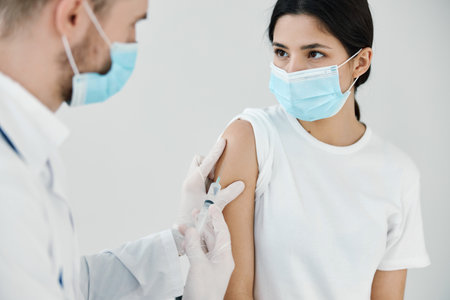 patient in medical mask in hospital and doctor vaccination injectionの写真素材