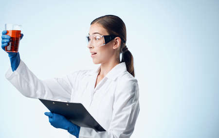 woman with liquid in a flask laboratory research chemical element Folder with documentsの写真素材