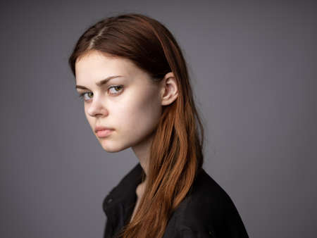 Woman in black coat portrait red hair gray background cropped viewの写真素材