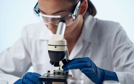 woman doctor in a medical gown and a microscope on the table glasses on the face laboratory researchの写真素材