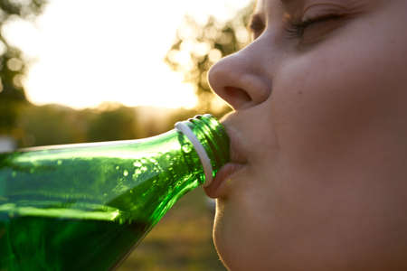 happy woman with bottle of water for invitation in garden close-up cropped viewの写真素材