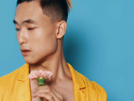 Portrait of a man in a yellow coat with a flower near his face and Asian appearanceの写真素材