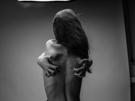 Woman black and white photography portrait rear view touching back with handsの写真素材