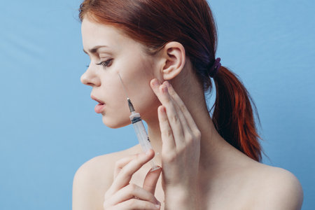 woman holding syringe near face botox rejuvenation injection blue background