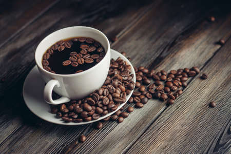saucer with coffee beans and white cup on a wooden table side view Copy Spaceの写真素材