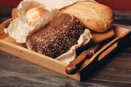 loaf of bread flour product on a tray on a wooden table and red background, pastriesの写真素材