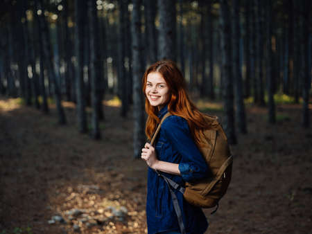 Happy woman hiker in the forest with a backpack on his back in autumn on natureの写真素材
