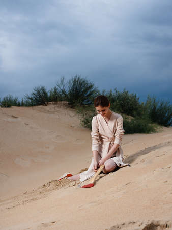 on the sand on a deserted beach a woman with an ax and a sundressの写真素材