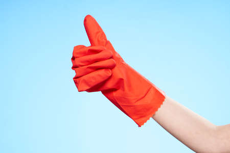 hand in red rubber gloves gesturing blue background cleaningの写真素材