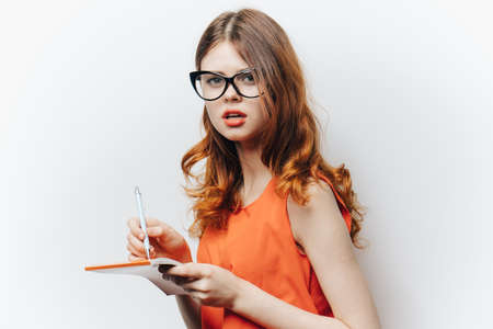 woman in orange shirt with notepad in hands fashion glassesの写真素材