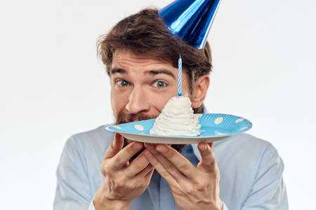 a man with a beard holds a cake in his hand on a light background birthdayの写真素材