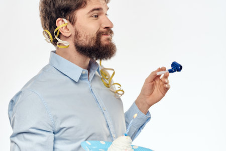A man with a cake plate and in a blue shirt on a light background birthday party corporate cap
