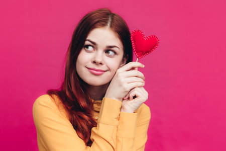Valentines day gifts woman with heart on stick on pink backgroundの写真素材