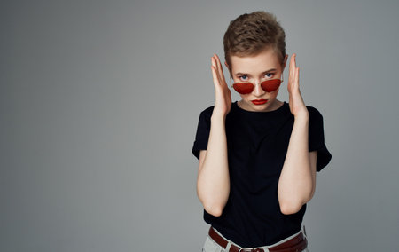 Woman with short hair and makeup dark glasses fashion black t-shirt gray backgroundの写真素材