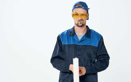 Man repairing paint roller blue suit and cap glassesの写真素材