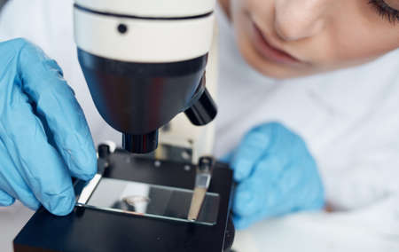 woman doctor in a medical gown and a microscope on the table glasses on the face laboratory researchの写真素材