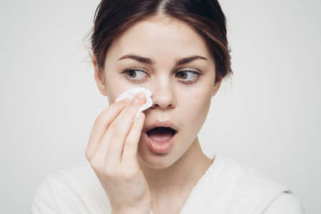 woman in a bathrobe wipes her face with a white sponge appearance care cosmetologyの写真素材