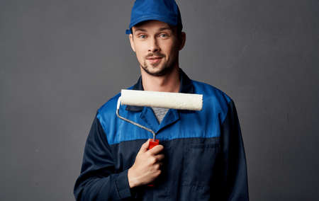A man repairs yellow glasses and a roller to paint the wallsの写真素材