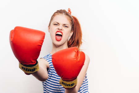 aggressive woman in red wrestling gloves on a light background wide open her mouth cropped viewの写真素材