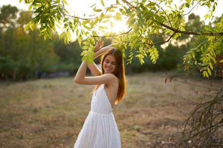 happy woman in a dress on nature near green leaves trees and bushes in the backgroundの写真素材