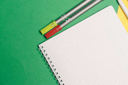 office supplies pens and notepads on yellow green backgroundの写真素材