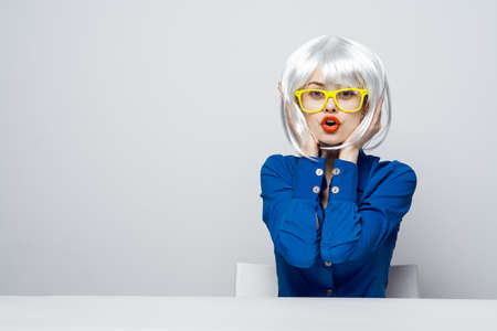 attractive woman in a white wig holds hands near the face red lips charm yellow glasses