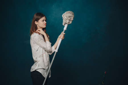 woman with mop on blue background gestures with hands emotionsの写真素材
