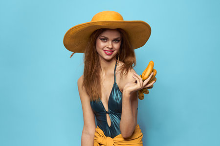 Woman in swimsuit hat exotic fruits summer fun blue background