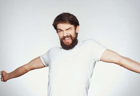 a man with a beard gestures with his hands on a light background Copy Space man