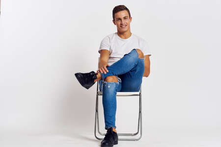 Man sitting on a chair fashionable clothes lifestyle light background