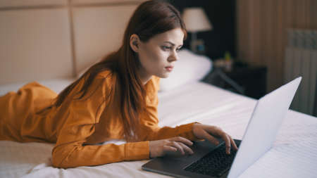 woman lying on bed in front of laptop rest internet communicationの写真素材