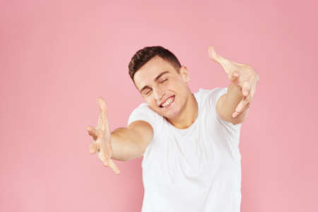 Emotional man gesturing with his hands white t-shirt pink isolated background