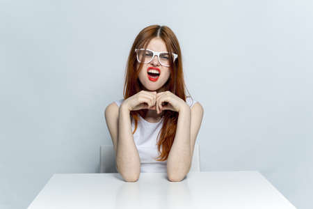 emotional red-haired woman sitting at table with open mouth lifestyle theme isolated background