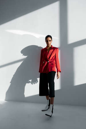 woman in fashionable red blazer and trousers autumn shoes light room